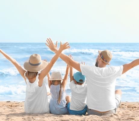 a family sitting on the beach with their hands in the air
