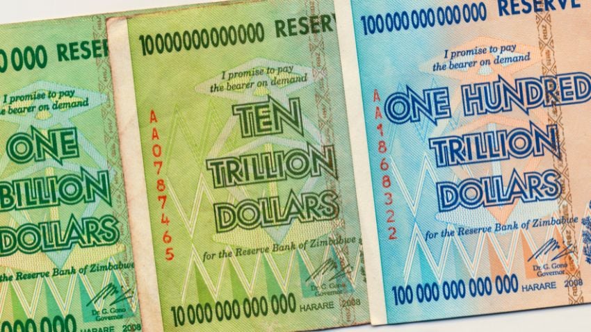 Notas bancárias do Zimbábue de trilhões de dólares, valor nominal absurdo devido à hiperinflação causada pela expansão da base monetária (impressão de dinheiro).
