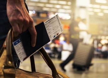 A person holding a passport and a travel ticket at the airport