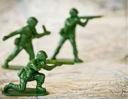 Green plastic toy soldiers positioned on a map, symbolizing military conflict or strategy planning.