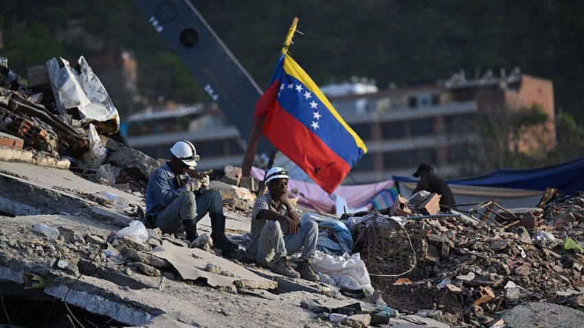 Rescue workers sit amid the rubble in Venezuela, where devastating earthquakes left thousands dead or homeless, raising serious questions about construction standards, building safety, and government oversight.