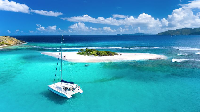 Aerial view of Catamaran at Sandy Spit - To become a resident, individuals must go through a process that includes securing a residence permit. This involves providing detailed information to the BVI authorities to demonstrate eligibility and compliance with immigration and residency regulations. The application process for a residence permit typically requires a valid passport, proof of financial stability, and a clean criminal record. Applicants must also meet specific requirements that demonstrate their intent to reside in the BVI, such as investing in local property or establishing a business. The BVI government closely scrutinizes each application to ensure that applicants genuinely intend to contribute to the local community and economy.